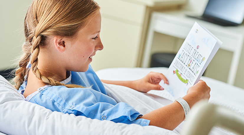 child in a hospital bed looking at a menu