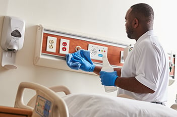 healthcare worker cleaning patient room